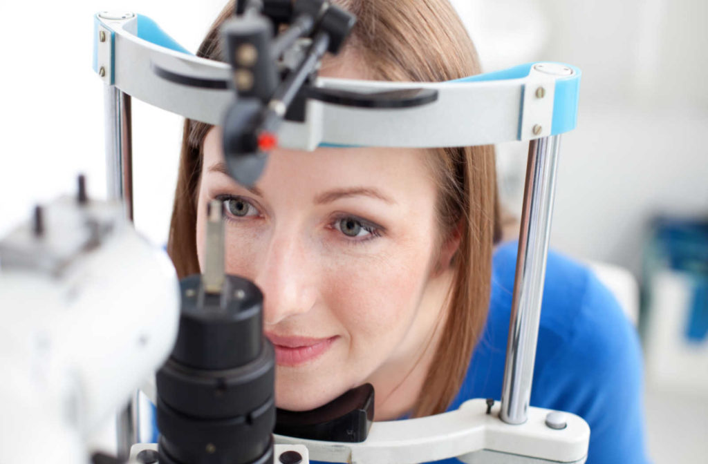 A young woman smiling getting her eyes examined during a slit lamp test.