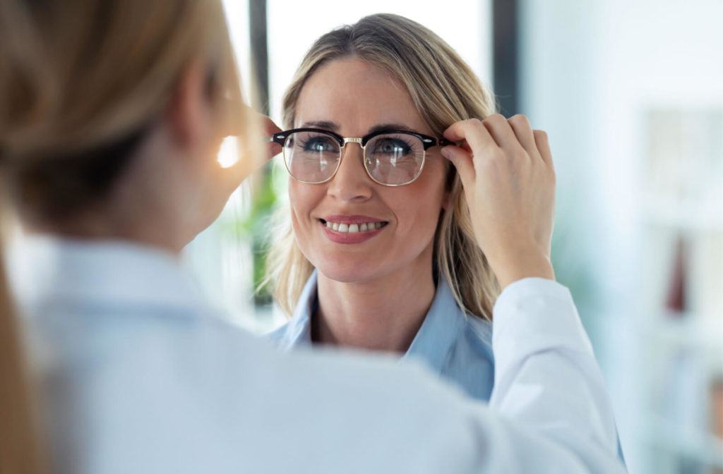 A woman gets her new prescribed eye glasses, her optometrist is fitting the eye glasses on her.