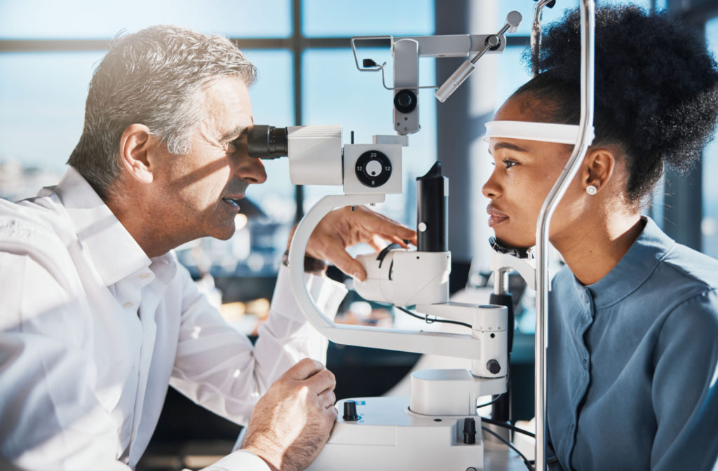 An optometrist looking at a patient's eyes during a comprehensive eye exam.