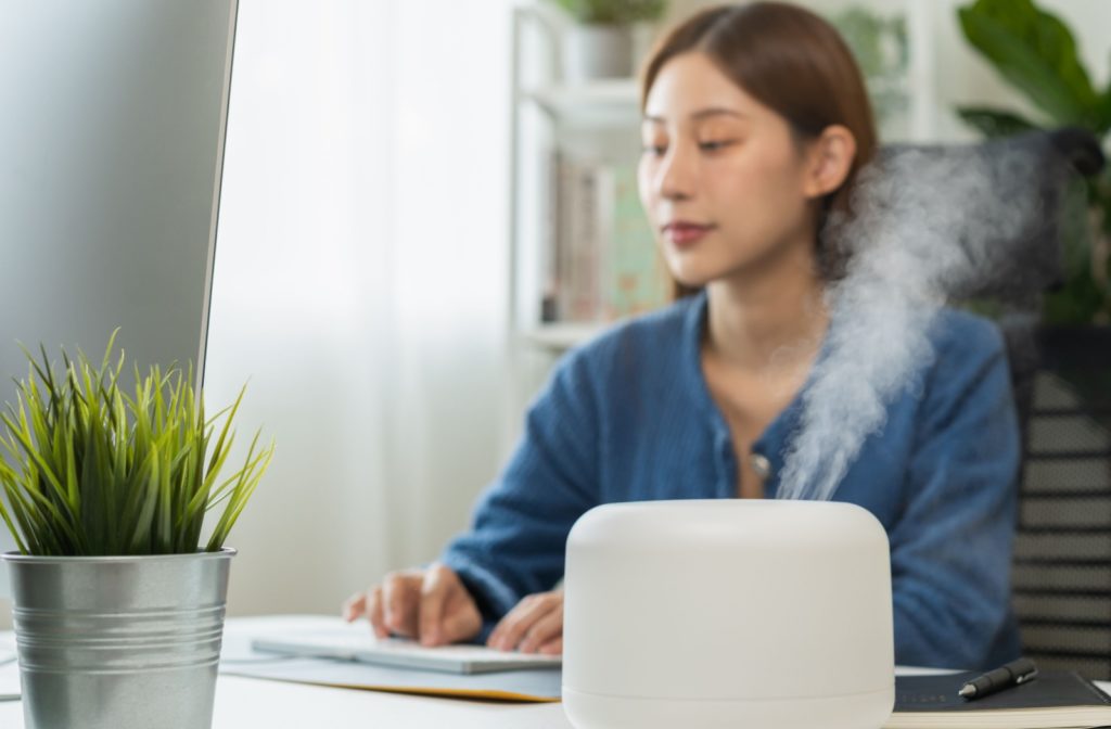 A person sitting at their desk with a humidifier to help with dry air in their workspace.