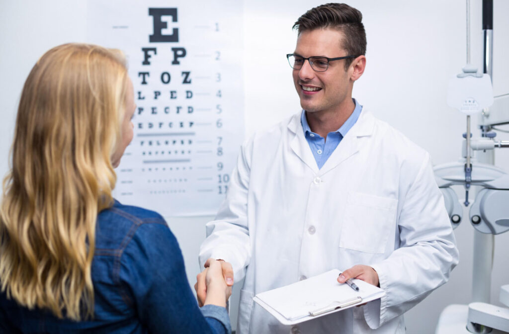 An eye doctor and patient shaking hands at an eye exam.