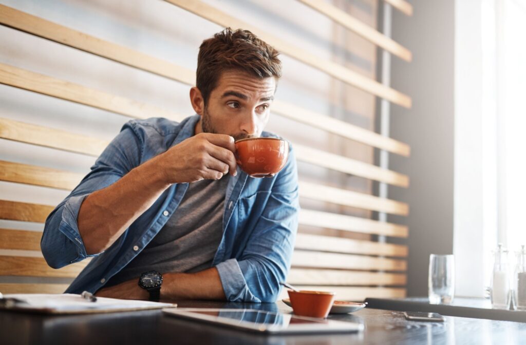 A person sitting at a table drinking a sip of coffee.